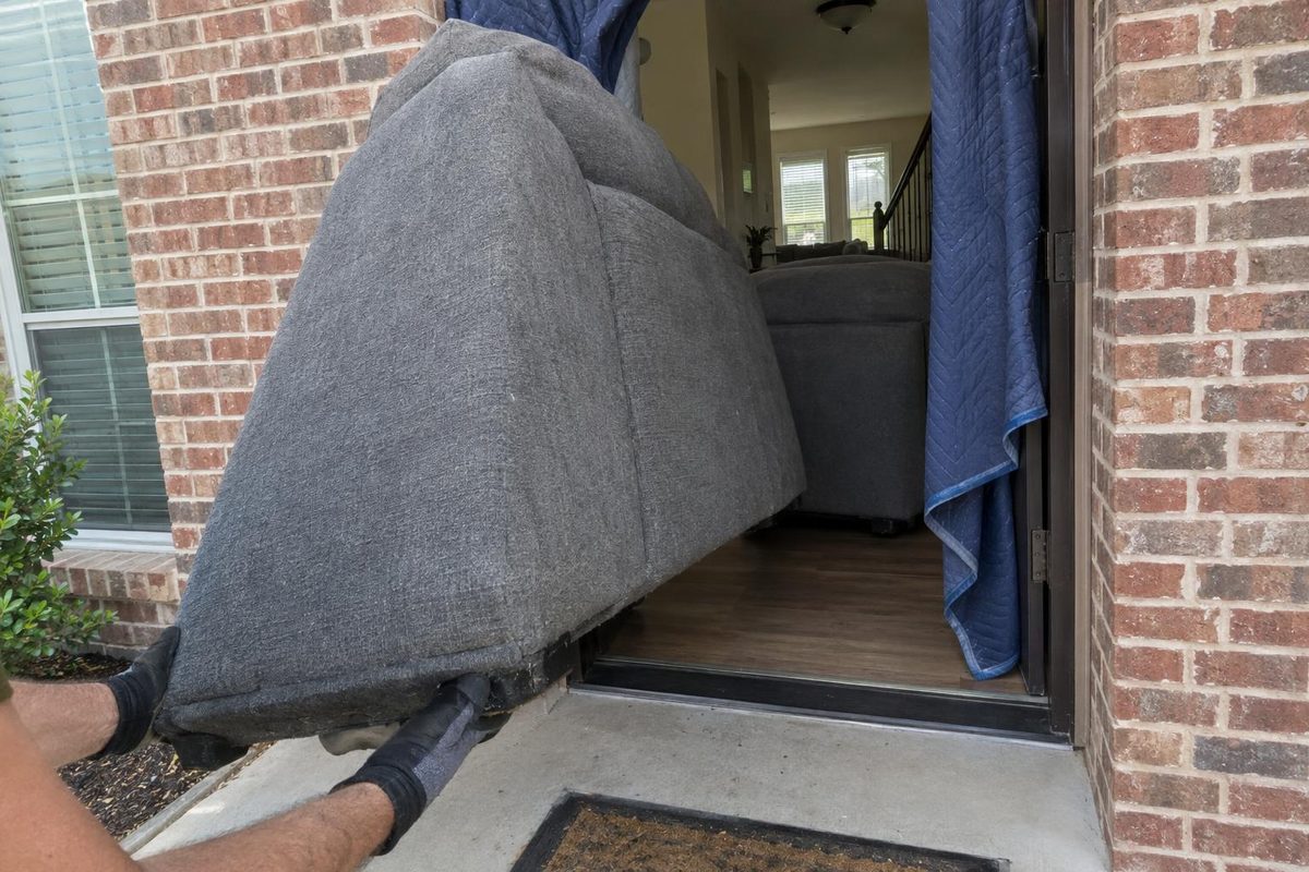 A section of a fabric sectional sofa tilted on end in an open front doorway